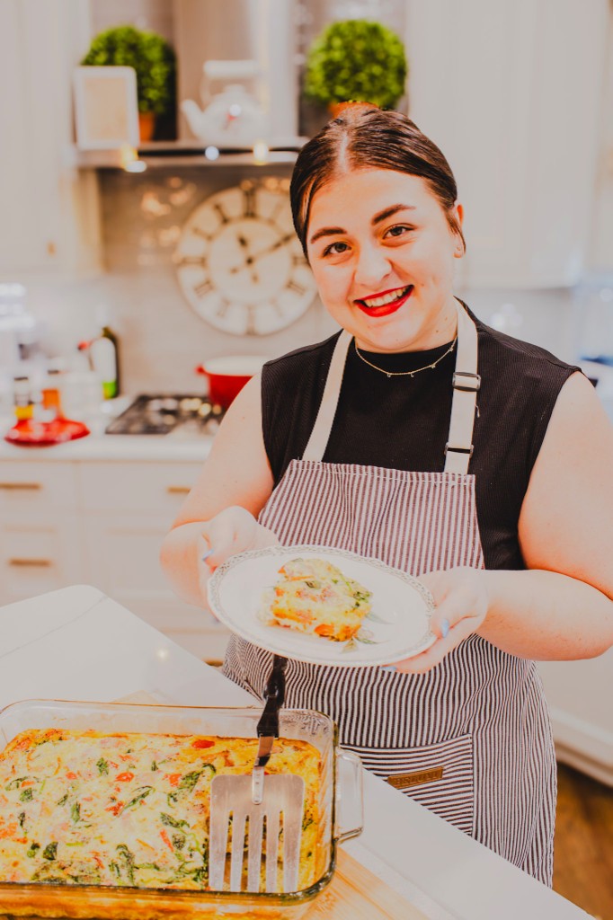 Kyla presenting a fresh slice of vegetable frittata in her kitchen